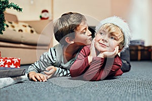 Okay, just because its Christmas you can kiss me. an adorable little boy giving his brother a kiss while waiting to open