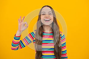 Okay. Portrait of teen girl making ok gesture, isolated background. Young teenager smiling and giving okey sign. Happy