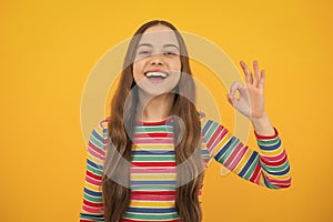 Okay. Portrait of teen girl making ok gesture, isolated background. Young teenager smiling and giving okey sign. Happy