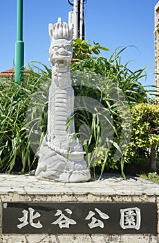 Okinawan Ryukyu dragon stone sculpture and stone sign where is inscribed Chatan Park in japanese on the sunset beach in the