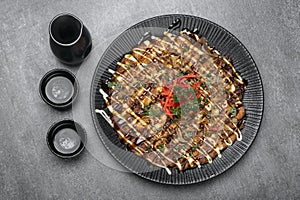 Okonomiyaki traditional japanese savoury pancake dish in restaurant on grey background