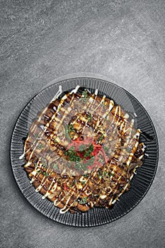 Okonomiyaki traditional japanese savoury pancake dish in restaurant on grey background