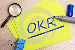 OKR - Objectives and Key Results - acronym text concept with marker on yellow business card