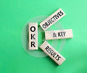 OKR objectives and key results symbol. Wooden blocks with words OKR objectives and key results. Beautiful green background.