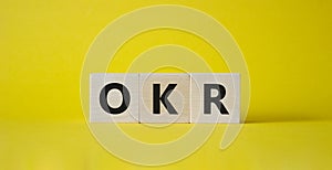 OKR objectives and key results symbol. Wooden cubes with words OKR objectives and key results. Beautiful yellow background.