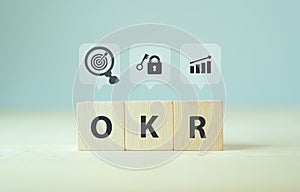 OKR text Objectives, Key and Results wooden cube block on grey background. Business target and drive business and performance. F