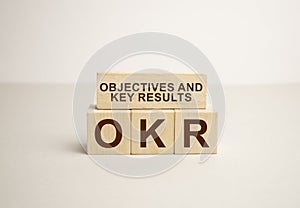 OKR word written on wood block. OKR word is made of wooden building blocks lying on the gray table, business concept. OKR short