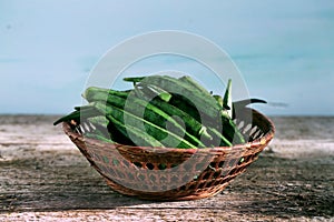 Okra or bhindi, bamia stacked in a basket on wood background