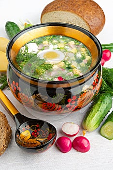 Okroshka summer cold yogurt soup in a wooden bowl. Radish, eggs, cucumber, green onions, dill. Top view. Khokhloma-style wooden