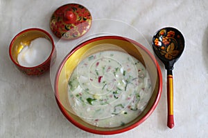 Okroshka. Traditional Russian summer cold soup with sausage, vegetables and kvass in bowl on wooden background. Top view