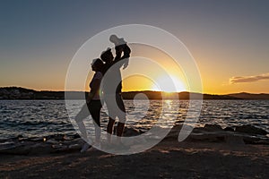 Okrug - Silhouette of loving parents holding small toddler at romantic sunset in Okrug Gornij, Split-Dalmatia, Croatia