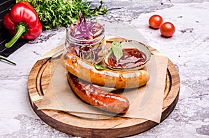 Oktoberfest food, german food. Sausage, ketchup, spiced red cabbage, red chili pepper, sauerkraut on wooden board at a pub.