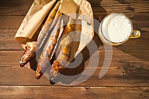 Oktoberfest holiday concept. Beer, smoked fish, chips on a wooden textural background in a dark key. Beer in a glass, fish in pape