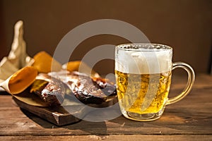 Oktoberfest holiday concept. Beer, smoked fish, chips on a wooden textural background in a dark key. Beer in a glass, fish in pape