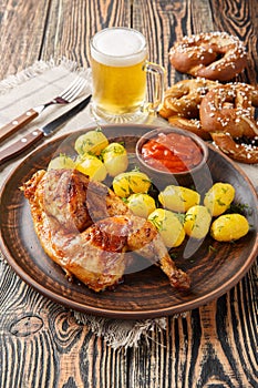 Oktoberfest Roast Chicken Wiesn Hendl with potatoes served with beer and pretzel closeup. Vertical