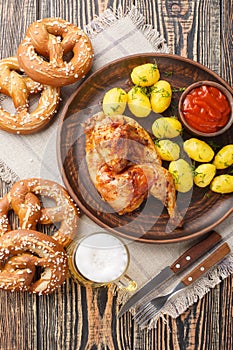 Oktoberfest Roast Chicken Wiesn Hendl with potatoes served with beer and pretzel closeup. Vertical top view