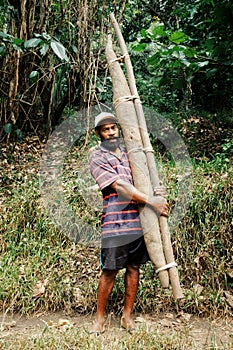 local villager farmer man with his big yam potato harvest at the edge of his tropical jungle garden