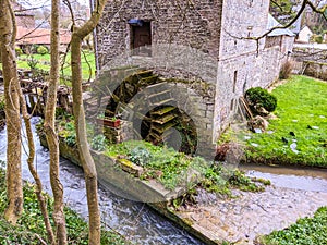 Old 18th century stone watermill with wooden wheel along the river Veules