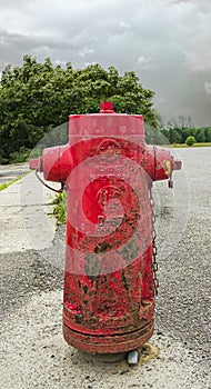 Old 1967 red Fire hydrant beside a sidewalk and road in a Quebec Village