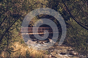 Old abandined metal bridge construction among the trees sunlit grove. Forest stream crossing. Stock photography photo