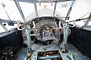 An old, abandoned airplane cockpit with handlebars and cranks