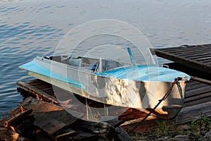 Old abandoned boat on the lake at sunset