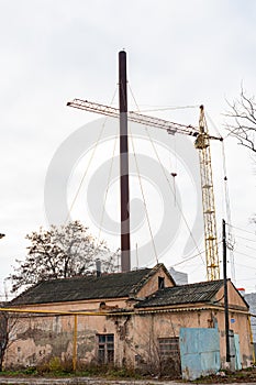 An old, abandoned boiler house building, and a construction, tower crane, in the background.