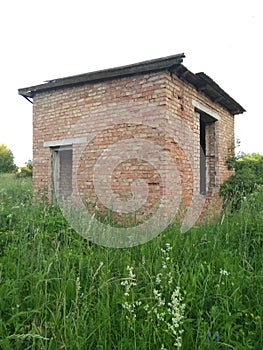 Old abandoned brick building in a field against the sky on a summer day