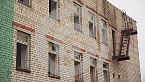Old abandoned brick building used for housing and rental apartments or hospital. Clip. Broken windows of a ruined house