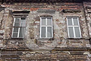 Old abandoned building with three windows. Aged brick wall. Vintage architecture concept. Ancient house.