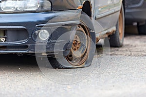 Old abandoned car with a rusting bottom and a flat wheel. Disposal and recycling of waste.