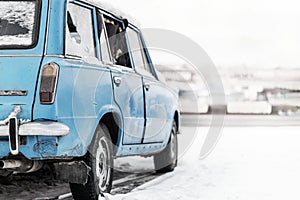 Old abandoned car station wagon blue in color with broken Windows. parked on the side of a winter road in the snow in