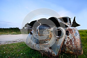 Old abandoned car under a blue sky