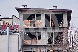 An old abandoned concrete unfinished house, with wooden props at Windows. Construction of private houses. Building demolished