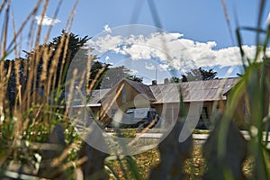 old abandoned estancia farm lying behind long gras with blue sky and clouds in patagonia