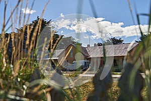 old abandoned estancia farm lying behind long gras with blue sky and clouds in patagonia