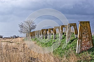 Old abandoned farm. Destroyed concrete structures. The gloomy landscape with lonely tree and the dark clouds.