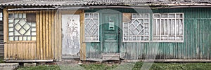 Old abandoned green wooden house facade with many doors and windows