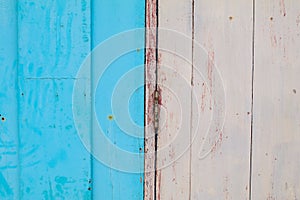 Old abandoned grunge vintage pastel white and red wooden window with blue wall yellow frame fixed with patches of rubber.