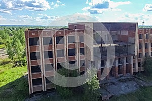 An old abandoned high rise building, overgrown with trees and gr