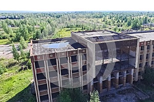 An old abandoned high rise building, overgrown with trees and gr