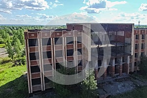 An old abandoned high rise building, overgrown with trees and gr