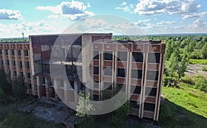 An old abandoned high rise building, overgrown with trees and grass