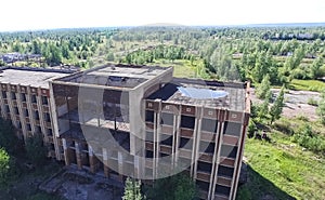 An old abandoned high rise building, overgrown with trees and grass