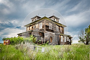 An old, abandoned home on the Saskatchewan prairies with a crib in the foreground