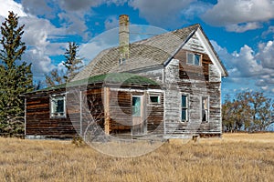 An old, abandoned home on the Saskatchewan prairieswith a crib in the foreground