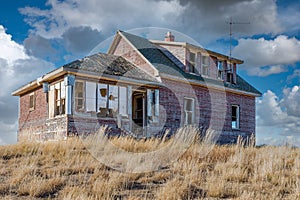 An old, abandoned home on the Saskatchewan prairieswith a crib in the foreground