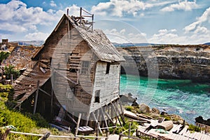 Old abandoned house on the edge of a cliff overlooking the sea with cliffs in the background