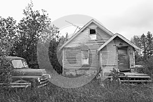 Old abandoned house with old truck sitting nearby.