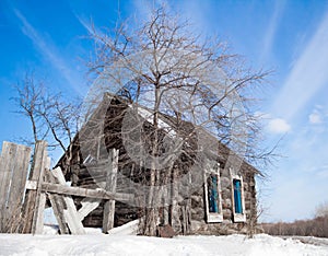 Old abandoned house with a tree. Blue sky. Winter